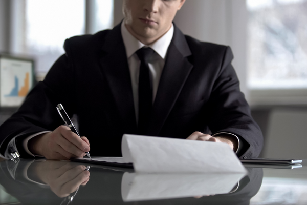 człowiek w garniturze podpisuje umowę
