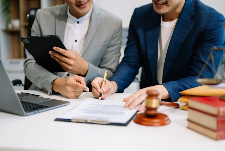 prawo restrukturyzacyjne - dwie osoby uśmiechnięte przy biurku z dokumentami